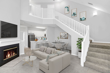 A living room with a staircase in the background and a couch in the foreground